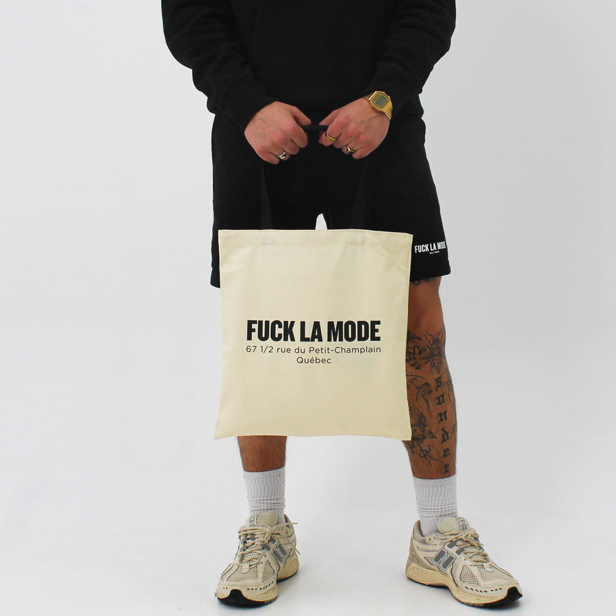 Beige Address tote bag with the “fuck la mode” logo and store address in black — streetwear clothing from Québec City.