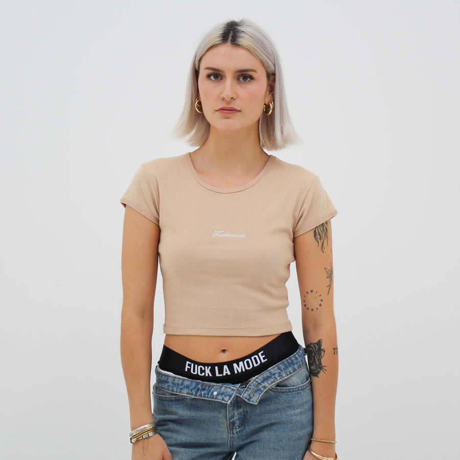 Almond baby tee with the “fuck la mode” script logo on the front — streetwear clothing from Québec City.