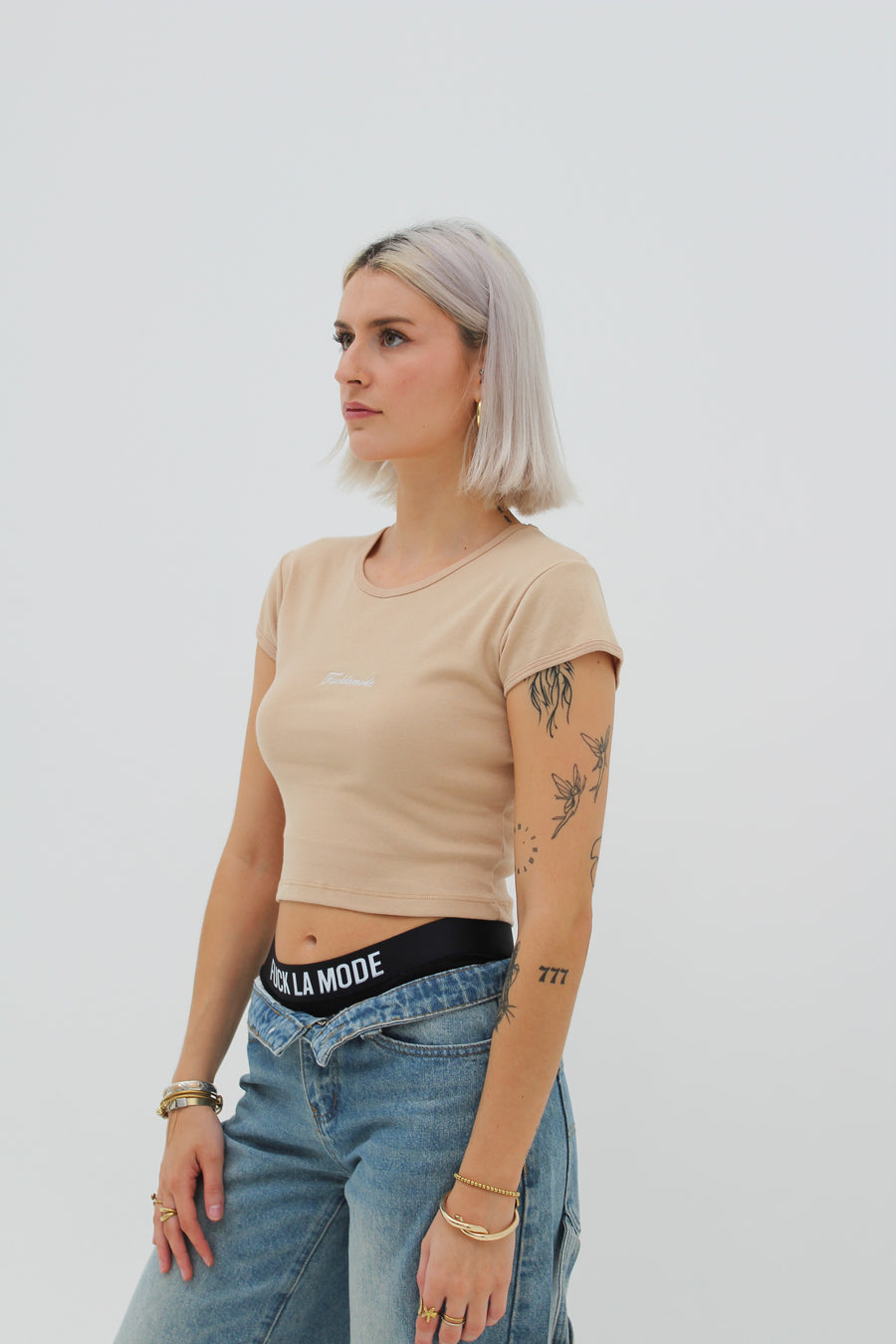 Almond baby tee with the “fuck la mode” script logo on the front — streetwear clothing from Québec City.