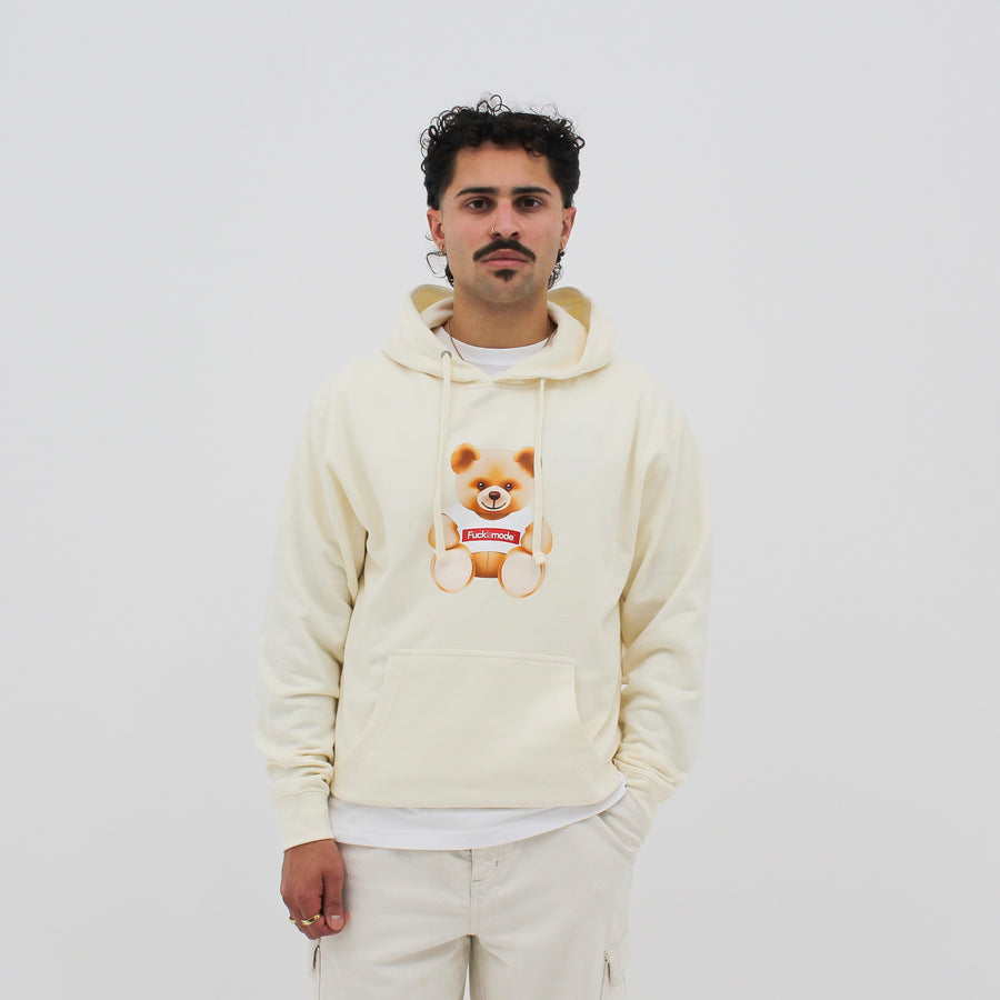 Cream “fuck la mode” hoodie with kangaroo pocket, hood drawstring, and the “fuck la mode” teddy bear at the center — streetwear clothing from Québec City.