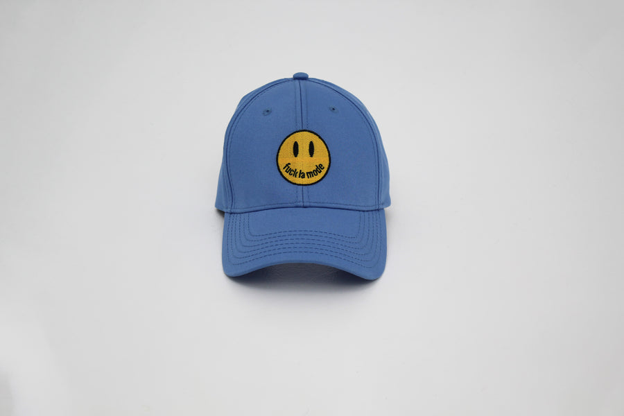 Blue trucker hat with a yellow smiley face “fuck la mode” — streetwear clothing from Québec City.