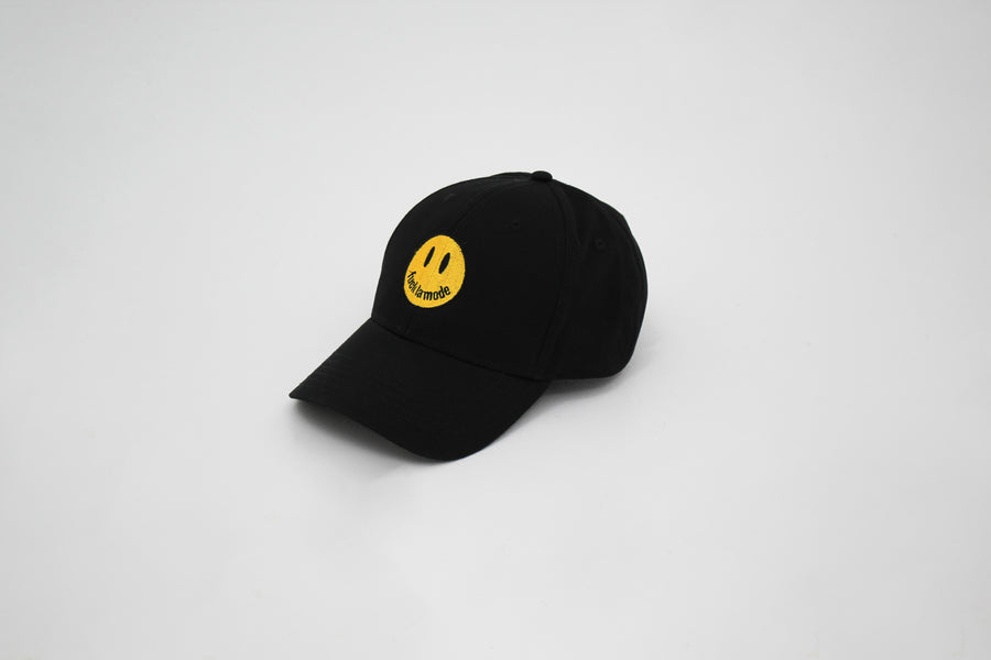 Black trucker hat with a yellow smiley face “fuck la mode” — streetwear clothing from Québec City.