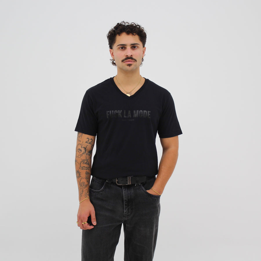 Black-on-black V-neck t-shirt with the retro “fuck la mode” logo — streetwear clothing from Québec City.