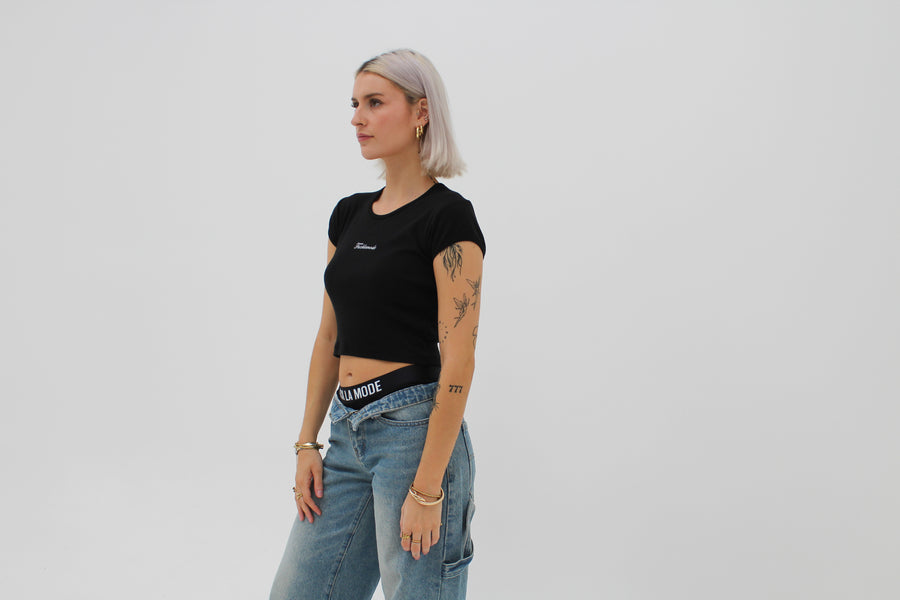 Black baby tee with the “fuck la mode” script logo on the front — streetwear clothing from Québec City.