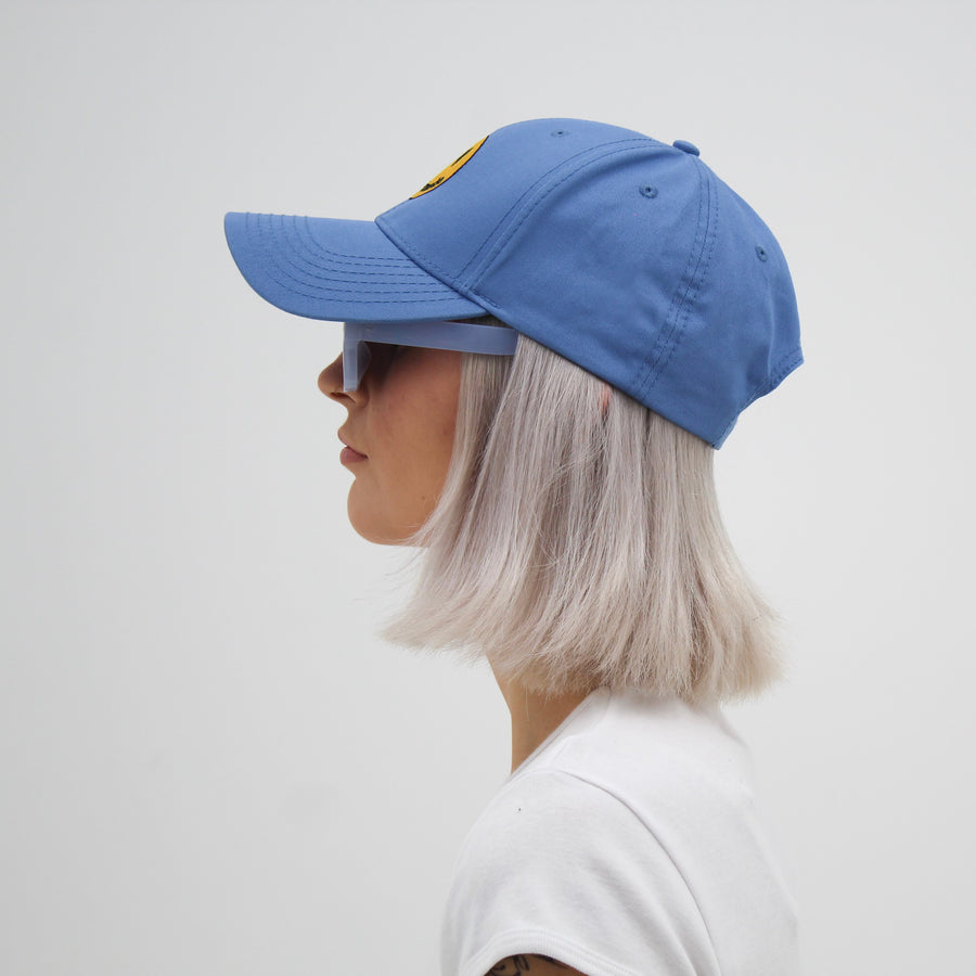 Blue trucker hat with a yellow smiley face “fuck la mode” — streetwear clothing from Québec City.