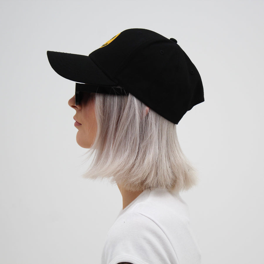 Black trucker hat with a yellow smiley face “fuck la mode” — streetwear clothing from Québec City.
